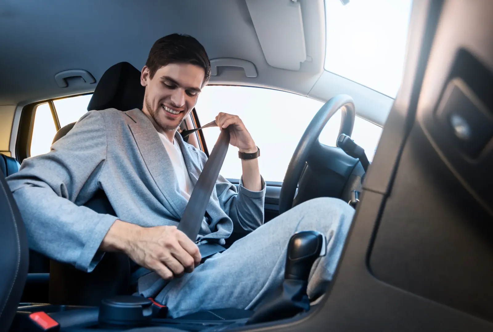 Vehicle occupant drawing the seat belt webbing across the torso before latching it into the buckle.